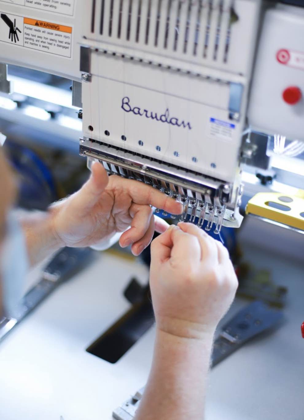 Man threads needle for embroidery machine