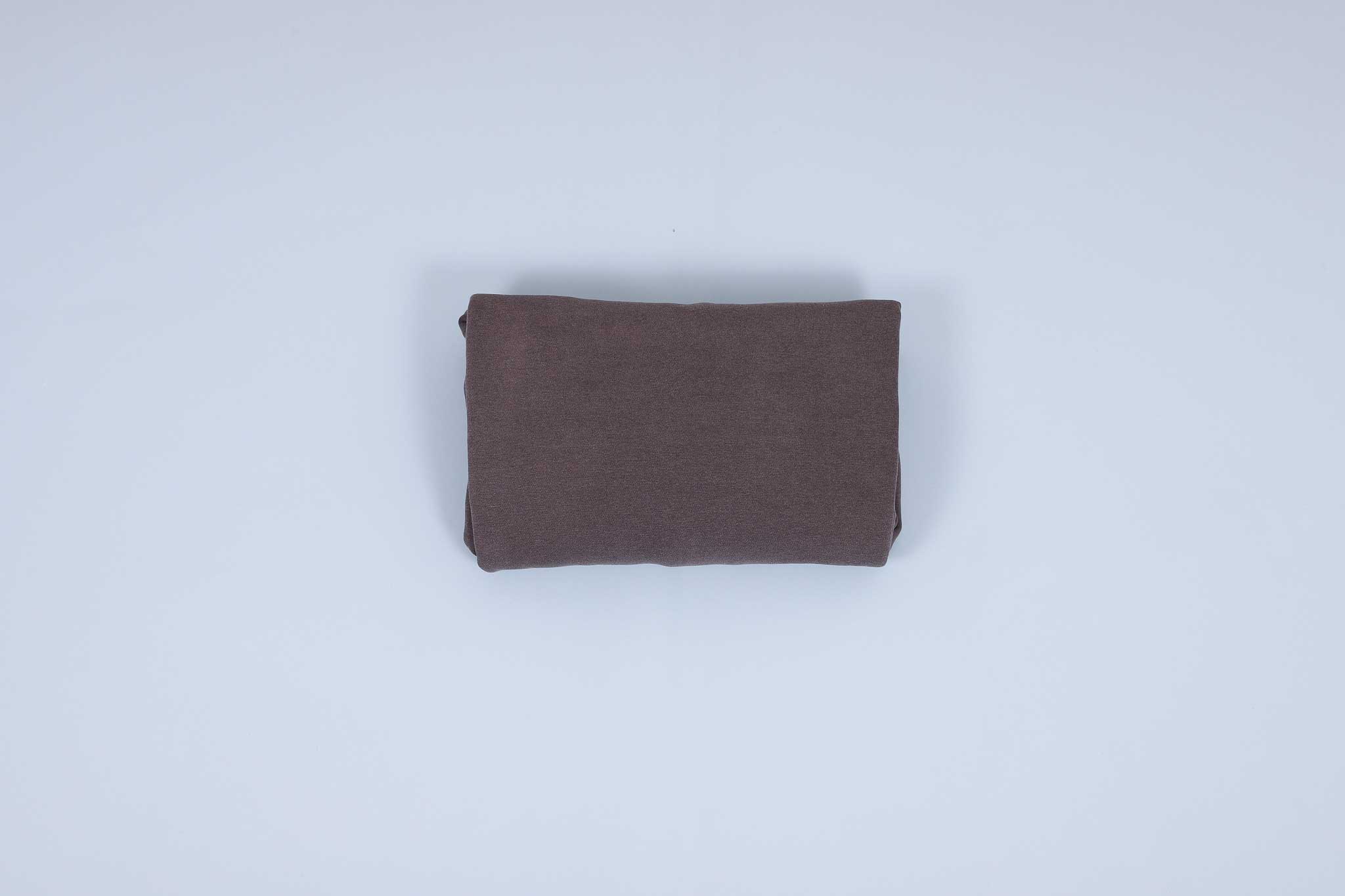 Grey sweater rolled up into thirds against a light blue background